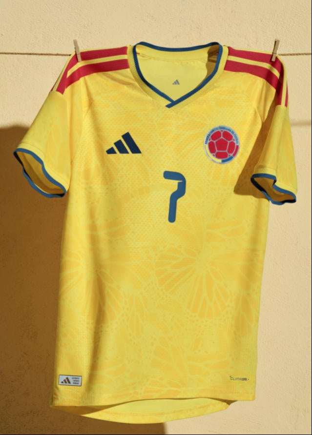 Soccer player wearing a yellow Colombia jersey with blue shorts on a grass field, next to a close-up of the jersey on a beige background.